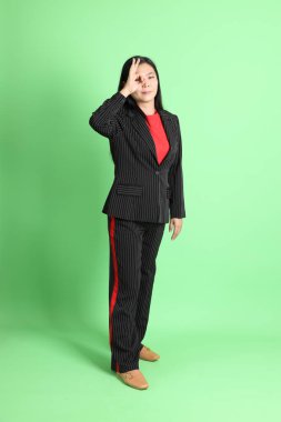 The Asian businesswoman standing on the pastel green background.