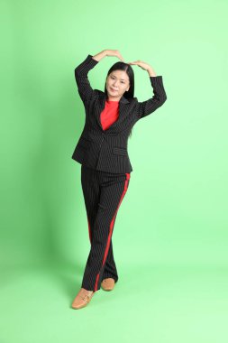 The Asian businesswoman standing on the pastel green background.