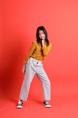 Turuncu arka planda sarı gömlekli genç Asyalı kız..