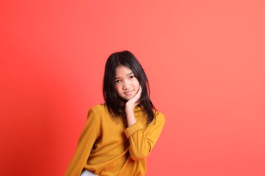 Turuncu arka planda sarı gömlekli genç Asyalı kız..