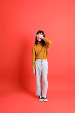 Turuncu arka planda sarı gömlekli genç Asyalı kız..