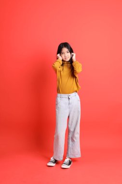 Turuncu arka planda sarı gömlekli genç Asyalı kız..