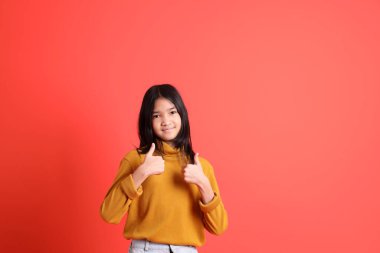 Turuncu arka planda sarı gömlekli genç Asyalı kız..