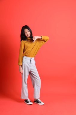 Turuncu arka planda sarı gömlekli genç Asyalı kız..