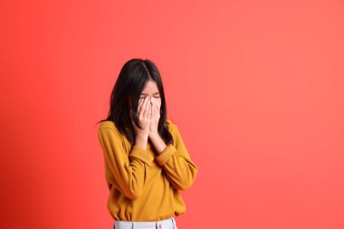 Turuncu arka planda sarı gömlekli genç Asyalı kız..