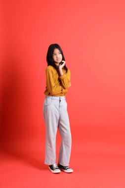 Turuncu arka planda sarı gömlekli genç Asyalı kız..