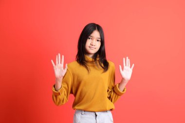 Turuncu arka planda sarı gömlekli genç Asyalı kız..