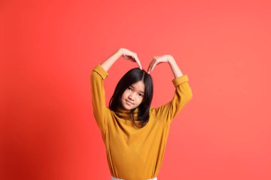 Turuncu arka planda sarı gömlekli genç Asyalı kız..