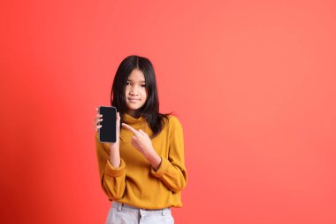 Turuncu arka planda sarı gömlekli genç Asyalı kız..