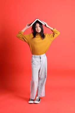 Turuncu arka planda sarı gömlekli genç Asyalı kız..