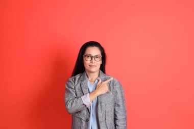 Turuncu arka planda duran Asyalı kıdemli iş kadını..