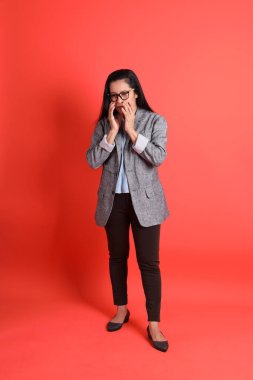 Turuncu arka planda duran Asyalı kıdemli iş kadını..