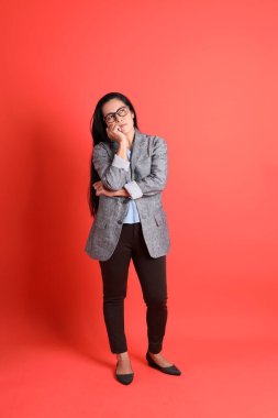 Turuncu arka planda duran Asyalı kıdemli iş kadını..