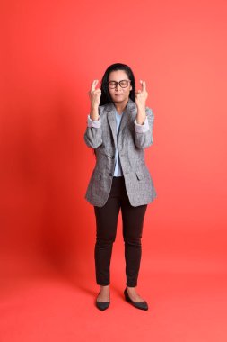 Turuncu arka planda duran Asyalı kıdemli iş kadını..