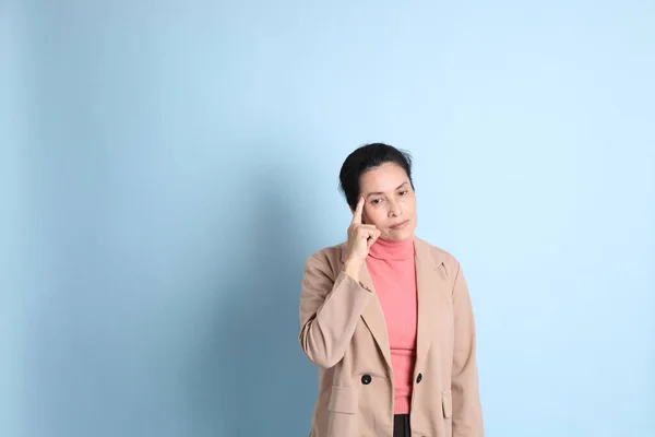 Senior Aziatische Vrouw Met Roze Shirt Bruine Blazer Blauwe Achtergrond — Stockfoto