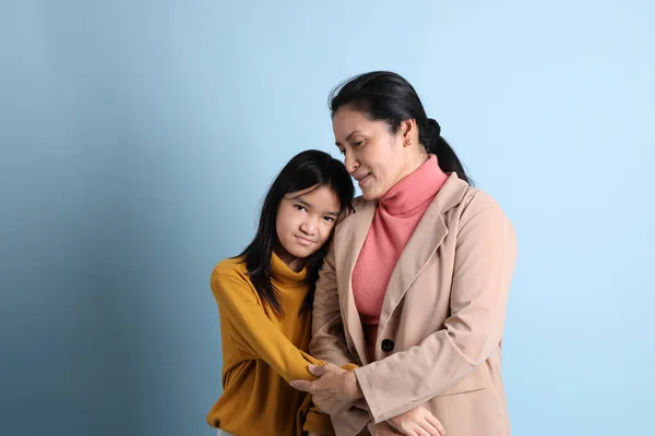 シニアアジアの娘抱擁彼女の母上の青の背景 — ストック写真