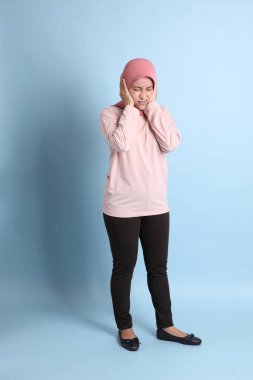 Mavi arka planda tesettürlü Güneydoğu Asyalı yaşlı kadın.