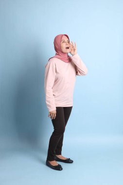 Mavi arka planda tesettürlü Güneydoğu Asyalı yaşlı kadın.