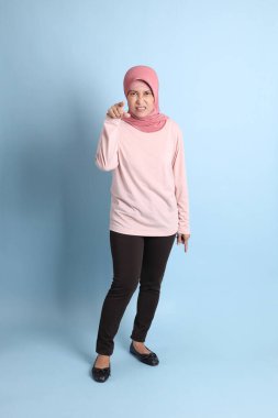 Mavi arka planda tesettürlü Güneydoğu Asyalı yaşlı kadın.