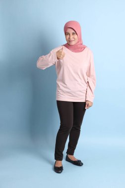 Mavi arka planda tesettürlü Güneydoğu Asyalı yaşlı kadın.