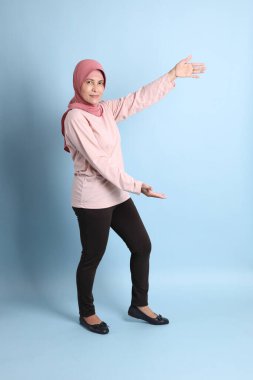 Mavi arka planda tesettürlü Güneydoğu Asyalı yaşlı kadın.