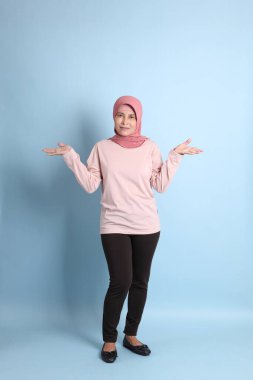 Mavi arka planda tesettürlü Güneydoğu Asyalı yaşlı kadın.