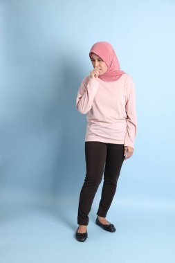 Mavi arka planda tesettürlü Güneydoğu Asyalı yaşlı kadın.