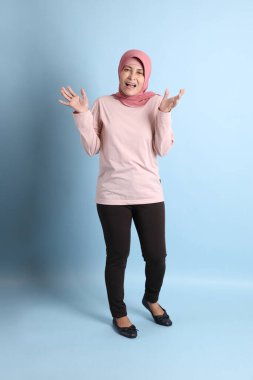 Mavi arka planda tesettürlü Güneydoğu Asyalı yaşlı kadın.