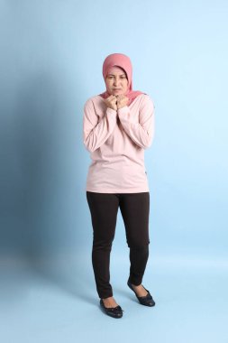 Mavi arka planda tesettürlü Güneydoğu Asyalı yaşlı kadın.