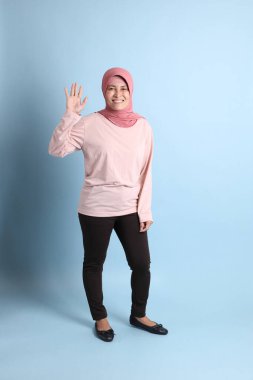 Mavi arka planda tesettürlü Güneydoğu Asyalı yaşlı kadın.