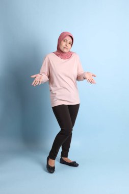 Mavi arka planda tesettürlü Güneydoğu Asyalı yaşlı kadın.