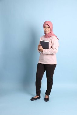 Mavi arka planda tesettürlü Güneydoğu Asyalı yaşlı kadın.