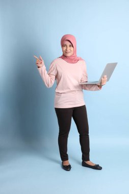 Mavi arka planda tesettürlü Güneydoğu Asyalı yaşlı kadın.