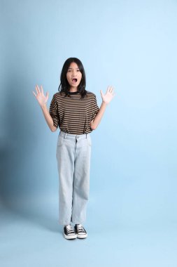 Mavi arka planda kahverengi gömlekli genç Asyalı kız..