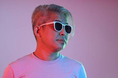 Neon ışıklı, güneş gözlüklü Asyalı adam.,