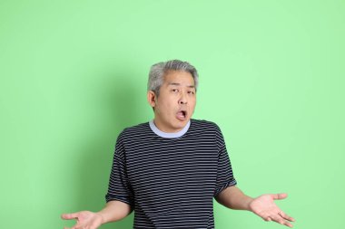 Yeşil arka planda sıradan tişörtlü 40 'lı yaşlardaki Asyalı adam..