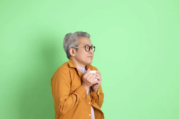 Yaşlarda Yeşil Arka Planda Duran Sarı Gömlekli Asyalı Bir Adam — Stok fotoğraf