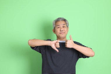 Yeşil arka planda sıradan tişörtlü 40 'lı yaşlardaki Asyalı adam..