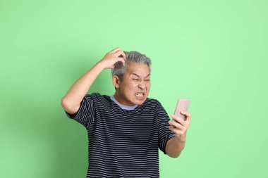 Yeşil arka planda sıradan tişörtlü 40 'lı yaşlardaki Asyalı adam..