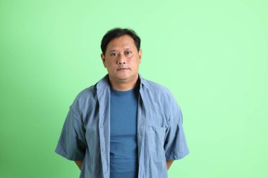 Yeşil arka planda duran 40 'lı yaşlardaki aşırı kilolu Asyalı adam..