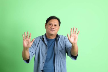 Yeşil arka planda duran 40 'lı yaşlardaki aşırı kilolu Asyalı adam..