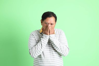 Yeşil arka planda duran 40 'lı yaşlardaki aşırı kilolu Asyalı adam..