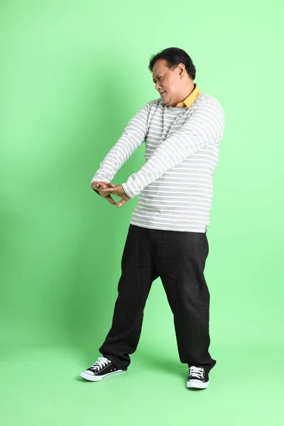 40多岁的亚洲超重男子站在绿色的背景上 — 图库照片
