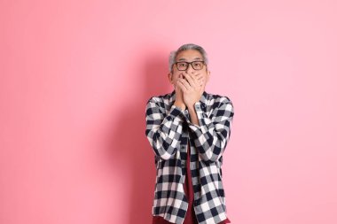 40 'lı yaşlarda Asyalı bir adam pembe arka planda sıradan kıyafetlerle dolanıyor..