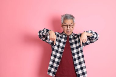 40 'lı yaşlarda Asyalı bir adam pembe arka planda sıradan kıyafetlerle dolanıyor..