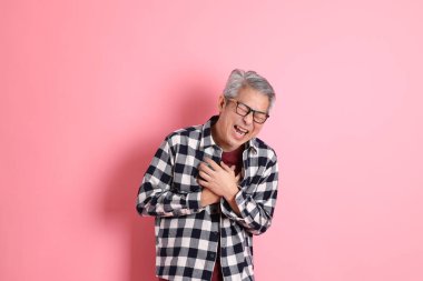 40 'lı yaşlarda Asyalı bir adam pembe arka planda sıradan kıyafetlerle dolanıyor..