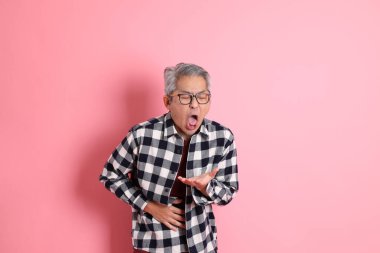 40 'lı yaşlarda Asyalı bir adam pembe arka planda sıradan kıyafetlerle dolanıyor..