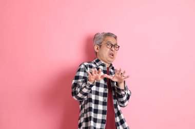 40 'lı yaşlarda Asyalı bir adam pembe arka planda sıradan kıyafetlerle dolanıyor..