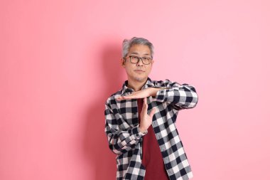 40 'lı yaşlarda Asyalı bir adam pembe arka planda sıradan kıyafetlerle dolanıyor..