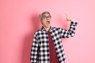 40 'lı yaşlarda Asyalı bir adam pembe arka planda sıradan kıyafetlerle dolanıyor..